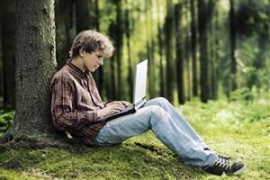 boy with laptop by tree